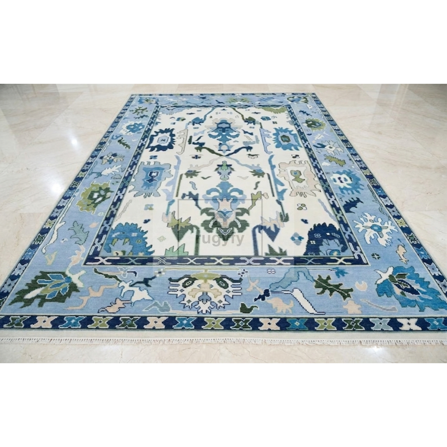 A rectangular area rug with an ornate traditional floral pattern in shades of blue, green, and cream, laid out on a polished light beige marble floor.