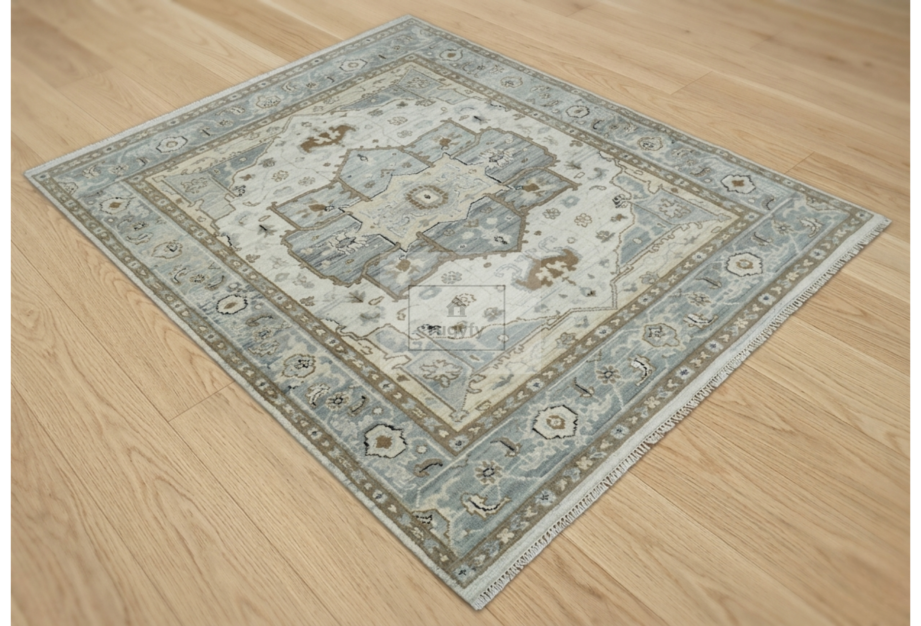 A rectangular area rug with an intricate traditional medallion pattern in muted blue, beige, and gray tones, shown laid out on a light wood floor.