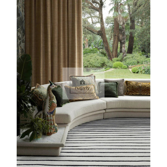 Black and ivory striped modern hand-tufted wool area rug in a contemporary living room with curved sofa