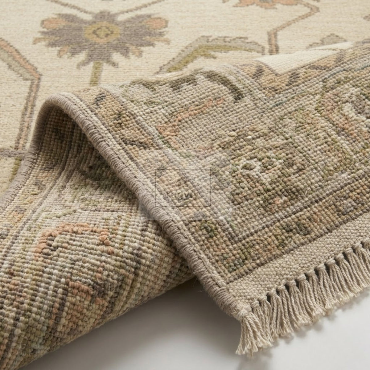 Corner fold of cream and soft taupe Sultanabad Oushak rug showing hand-knotted wool back, woven foundation and natural fringe - RUGYFY