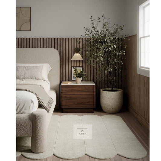 Sage green scalloped edge plush hand-tufted wool rug beside a boucle bed in a modern bedroom